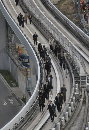 Yurikamome train passengers walk on the elevated track towards Shiodome Station in Tokyo's Shiodome district near Tokyo Bay Friday, March 11, 2011, shortly after a 7.9-magnitude earthquake has struck off Japan's northeastern coast. (AP Photo/Koji Sasahara)