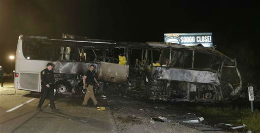 A pair of California Highway Patrol Officers walk past the burned out tour bus that crashed into a FedEx truck on Interstate 5 Thursday, April 10, 2014, in Orland, Calif. (AP Photo/Rich Pedroncelli)