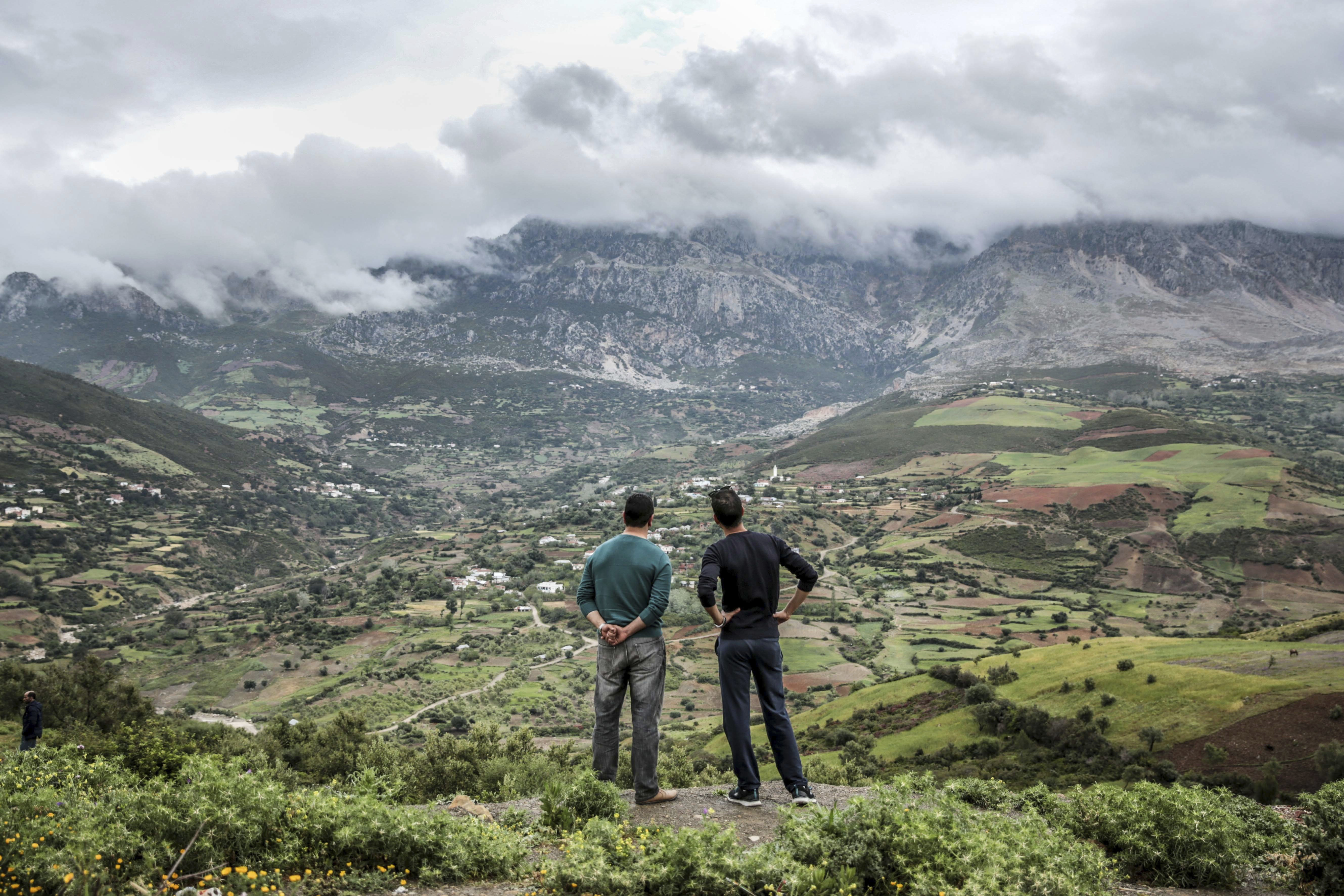 Two men observe rainclouds hanging over the Rif mountains near Tetouan, northern Morocco