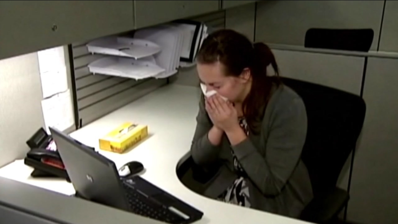 A woman sneezes into a tissue at her desk in this undated file photo.