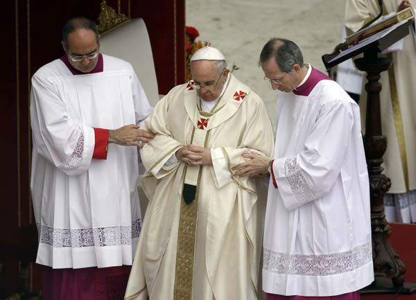 Pope Francis is helped while presiding over a solemn ceremony in St. Peter's Square at the Vatican, Sunday, April 27, 2014. Pope Francis has declared his two predecessors John XXIII and John Paul II saints in an unprecedented canonization ceremony made even more historic by the presence of retired Pope Benedict XVI. (AP Photo/Gregorio Borgia)
