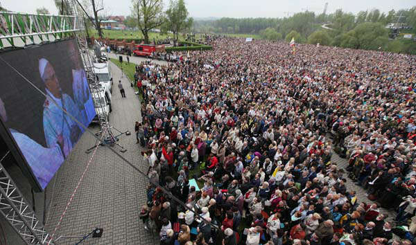 Crowds gather in God's Mercy sanctuary in Krakow, Poland, on Sunday, April 27, 2014, for ceremonies of canonization of Polish-born Pope John Paul II. Thousands of faithful flocked to the sanctuary to watch live from the Vatican as Pope Francis, aided by emeritus Pope Benedict XVI declares John Paul and John XXIII saints, in an unprecedented ceremony involving four popes. (AP Photo/Czarek Sokolowski)
