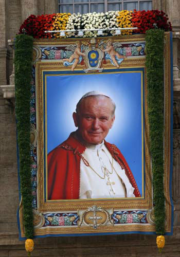A tapestry with the portrait of Pope John Paul II hangs from the facade of St. Peter's Basilica, at the Vatican Sunday, April 27, 2014. Pope Francis has declared his two predecessors John XXIII and John Paul II saints in an unprecedented canonization ceremony made even more historic by the presence of retired Pope Benedict XVI. (AP Photo/Domenico Stinellis)