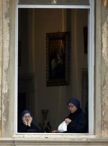Nuns watch from a window in St. Peter's Square at the Vatican, Sunday, April 27, 2014. Tens of thousands of people have filled St. Peter's Square for a historic day of four popes, with Popes Francis and Benedict XVI honoring John XXIII and John Paul II by declaring them saints in the first ever canonization of two pontiffs. (AP Photo/Gregorio Borgia)