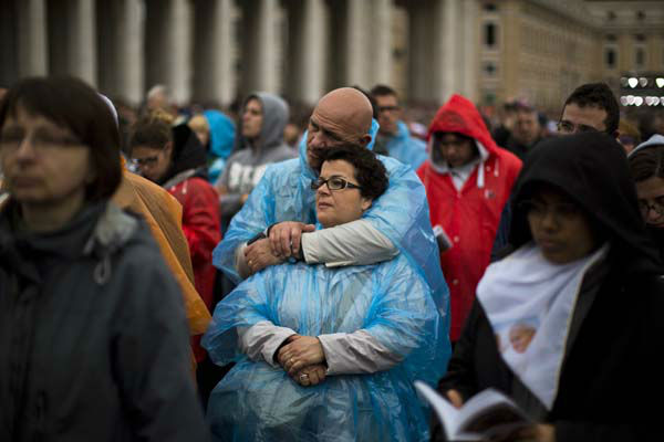 People pray as Pope Francis leads a solemn ceremony in St. Peter's Square at the Vatican Sunday, April 27, 2014. Pope Francis has declared his two predecessors John XXIII and John Paul II saints in an unprecedented canonization ceremony made even more historic by the presence of retired Pope Benedict XVI. (AP Photo/Emilio Morenatti)