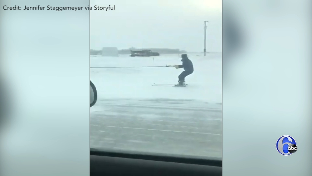 Man on skis pulled by horse and buggy