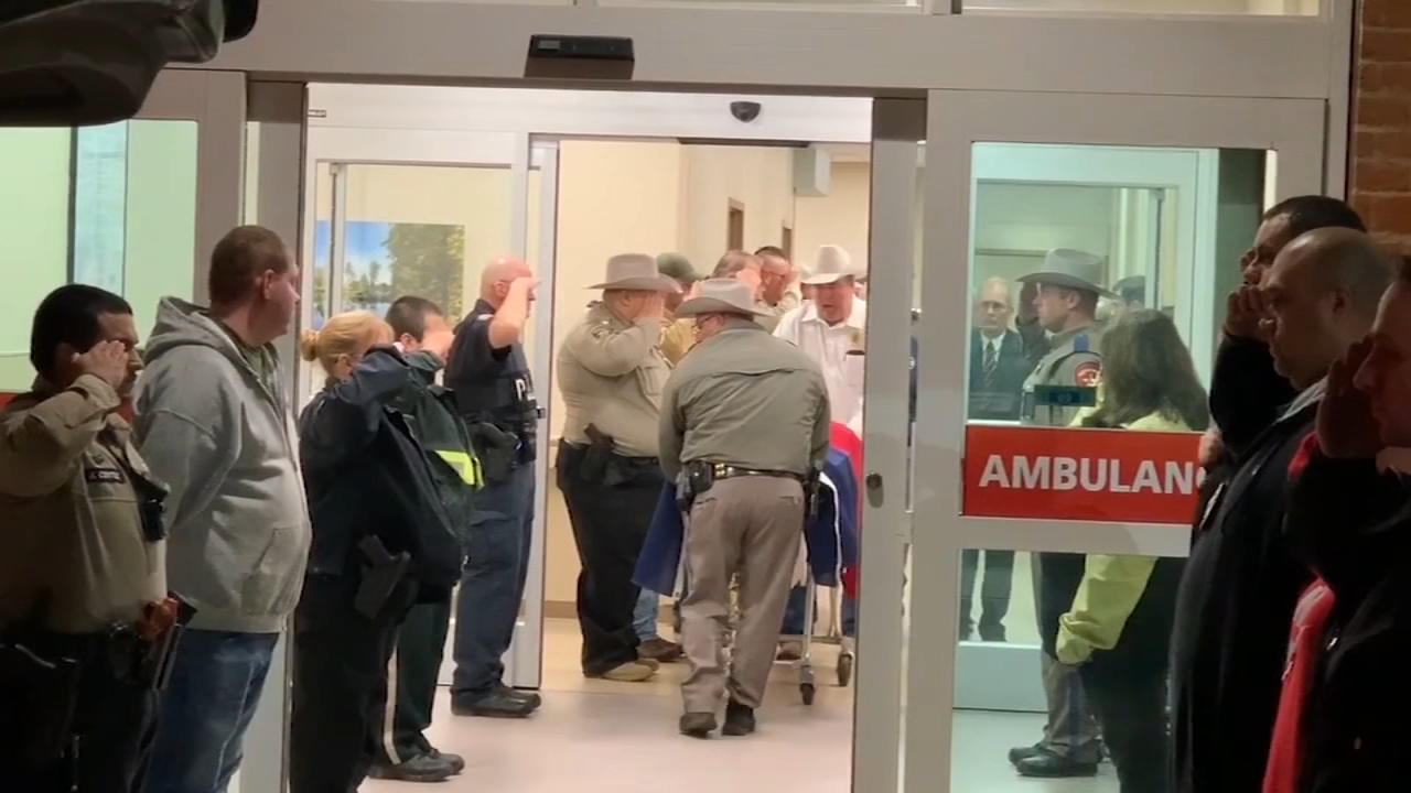 Officers salute the casket of fallen San Jacinto Co. Deputy