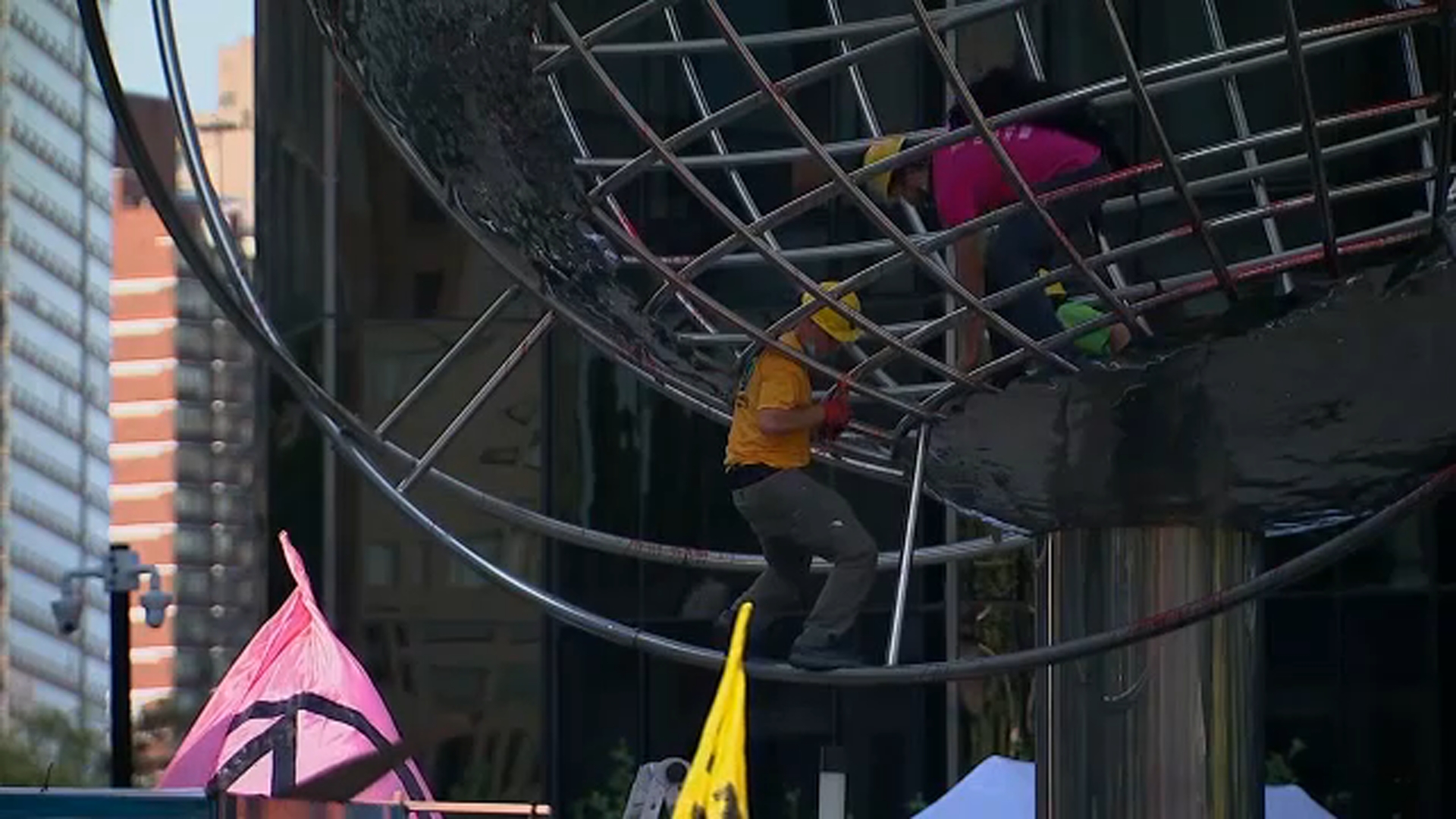 Climate change protesters climb globe sculpture outside Trump hotel