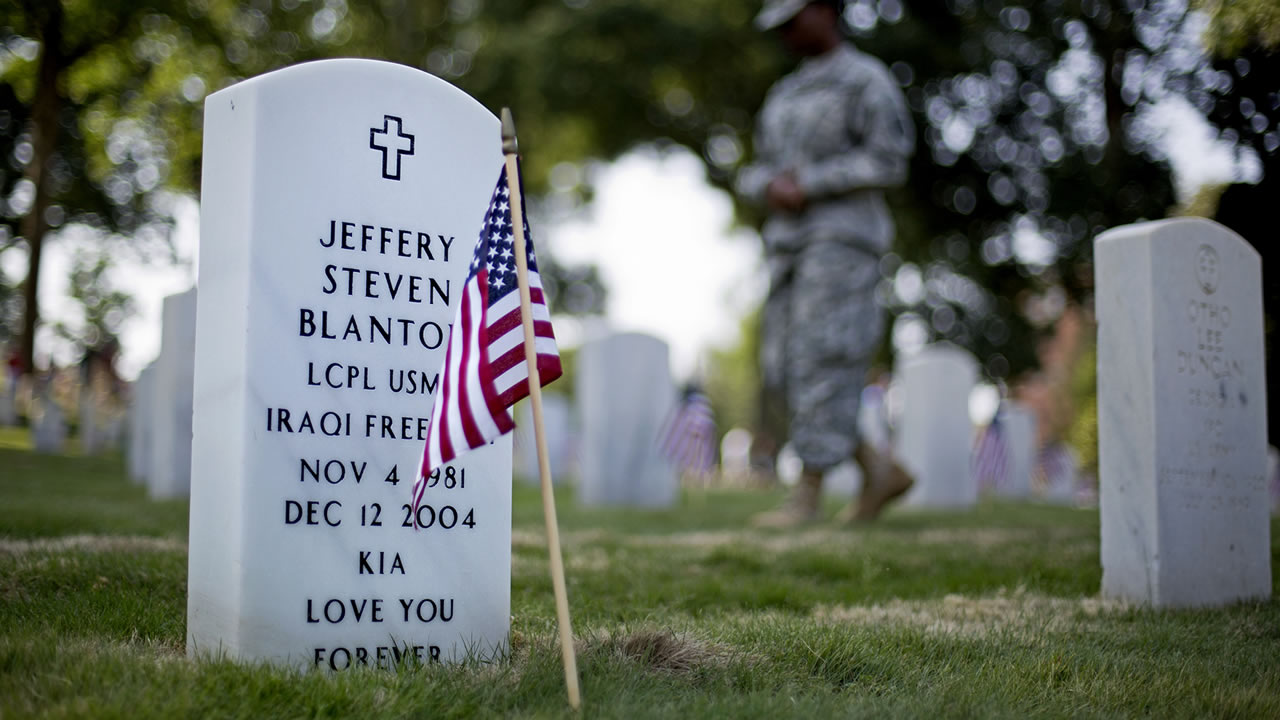 A soldier walks past the grave of U.S. Marine Lance Cpl. Jeffery Blanton Monday, May 26, 2014, at Marietta National Cemetery in Marietta, Ga. (AP Photo/David Goldman)