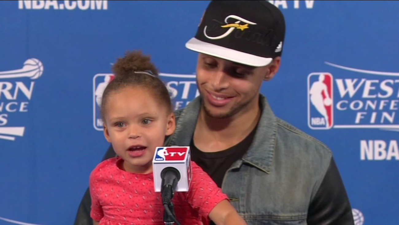 File photo - Warriors' Stephen Curry speaks at a press conference while he hold his daughter.