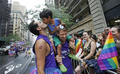 Rafael Gondim, left, kisses his five year-old son Gabriel King, as his husband Courtney King holds the child.