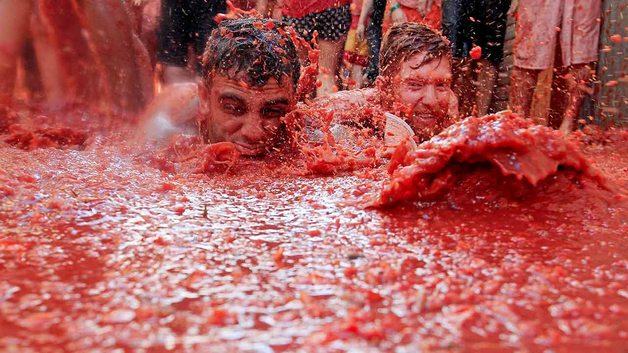 Two men lie in a puddle of squashed tomatoes, during the annual "tomatina" tomato fight fiesta, in the village of Bunol, 50 kilometers outside Valencia, Spain on Aug. 26, 2015.