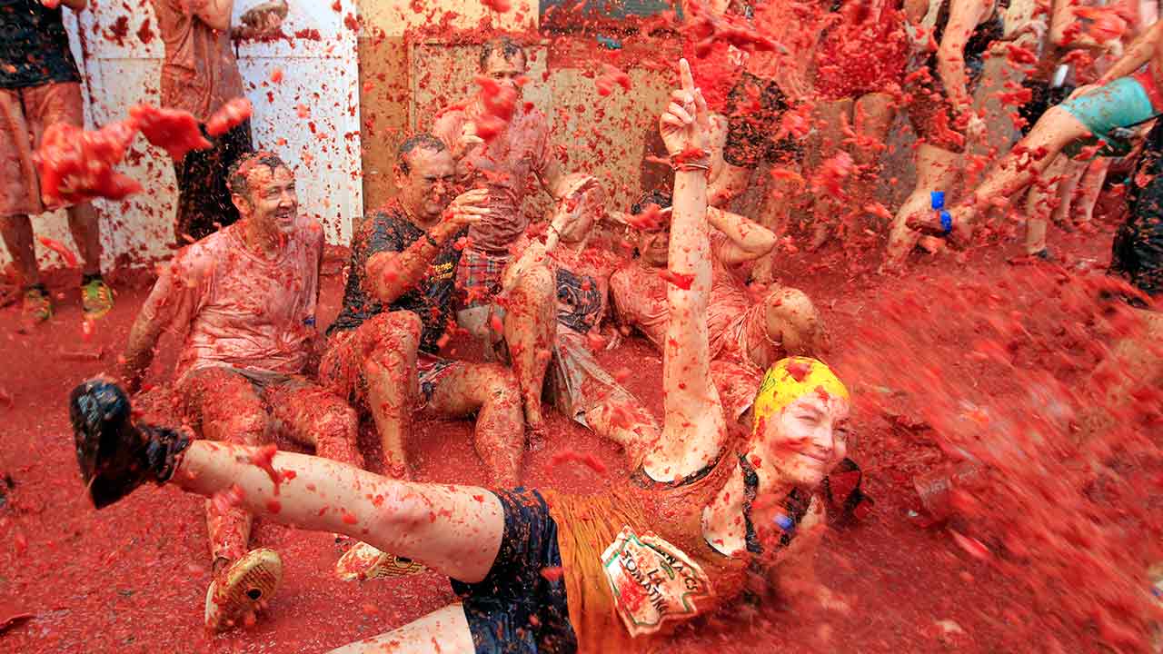 People sit and lie on the ground during the annual "tomatina" tomato fight fiesta, in the village of Bunol, 50 kilometers outside Valencia, Spain on Aug. 26, 2015.