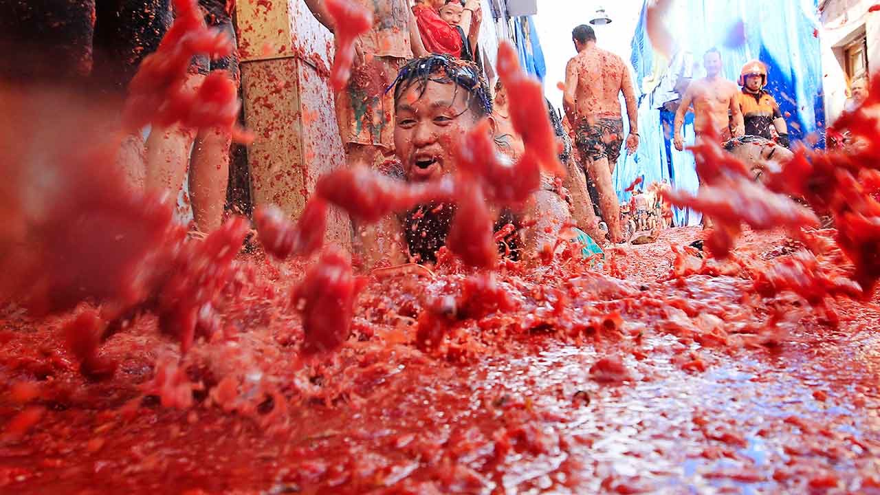 People lie in a puddle of squashed tomatoes, during the annual "tomatina" tomato fight fiesta, in the village of Bunol, 50 kilometers outside Valencia, Spain on Aug. 26, 2015.